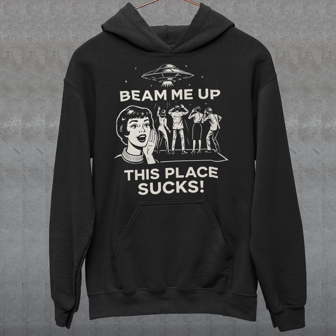 This snark-powered retro UFO hoodie brings the perfect escape fantasy to life. A vintage-style flying saucer hovers above a crowd while a wide-eyed woman rallies for interstellar rescue, paired with the bold line “Beam Me Up, This Place Sucks!” The design has a classic pulp-sci-fi look that feels like it tumbled out of an old comic rack. Ideal for anyone who survives their days with eye rolls, cosmic daydreams, and a desire to be anywhere else in the galaxy.