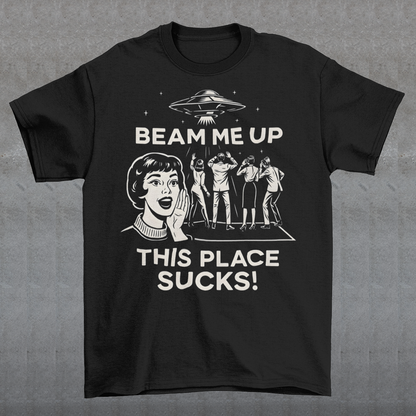 This snark-powered retro UFO t-shirt brings the perfect escape fantasy to life. A vintage-style flying saucer hovers above a crowd while a wide-eyed woman rallies for interstellar rescue, paired with the bold line “Beam Me Up, This Place Sucks!” The design has a classic pulp-sci-fi look that feels like it tumbled out of an old comic rack. Ideal for anyone who survives their days with eye rolls, cosmic daydreams, and a desire to be anywhere else in the galaxy.