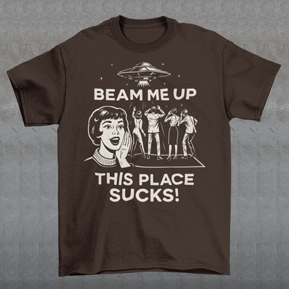 This snark-powered retro UFO t-shirt brings the perfect escape fantasy to life. A vintage-style flying saucer hovers above a crowd while a wide-eyed woman rallies for interstellar rescue, paired with the bold line “Beam Me Up, This Place Sucks!” The design has a classic pulp-sci-fi look that feels like it tumbled out of an old comic rack. Ideal for anyone who survives their days with eye rolls, cosmic daydreams, and a desire to be anywhere else in the galaxy.