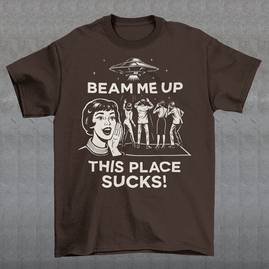 This snark-powered retro UFO t-shirt brings the perfect escape fantasy to life. A vintage-style flying saucer hovers above a crowd while a wide-eyed woman rallies for interstellar rescue, paired with the bold line “Beam Me Up, This Place Sucks!” The design has a classic pulp-sci-fi look that feels like it tumbled out of an old comic rack. Ideal for anyone who survives their days with eye rolls, cosmic daydreams, and a desire to be anywhere else in the galaxy.
