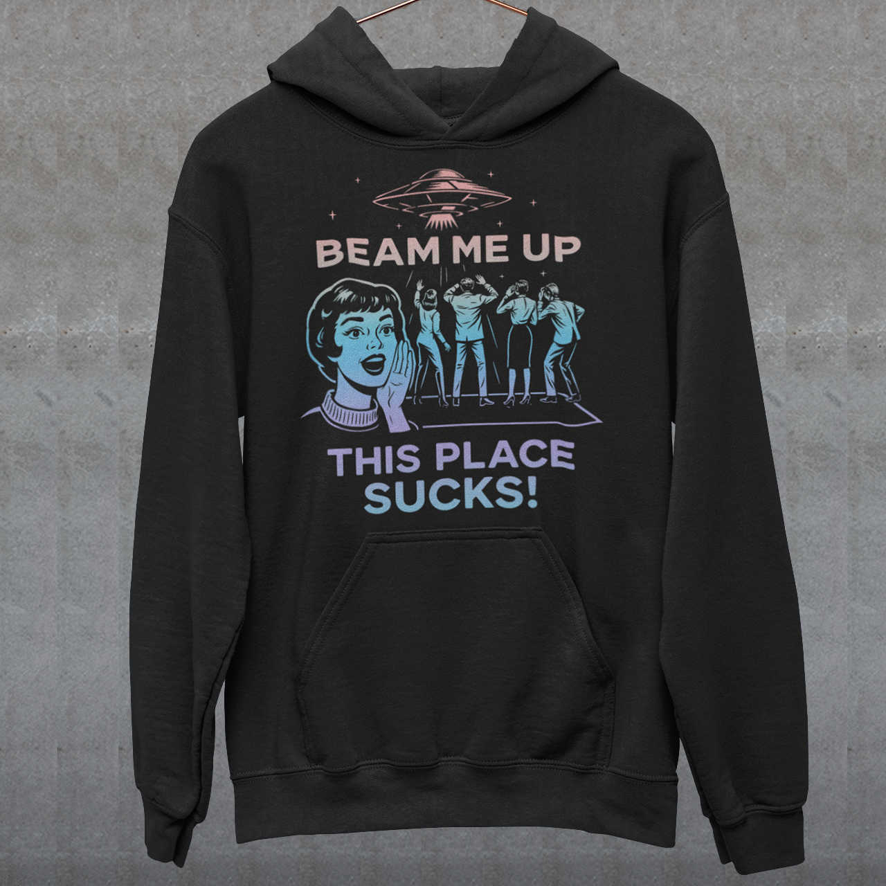 This snark-powered retro UFO hoodie brings the perfect escape fantasy to life. A vintage-style flying saucer hovers above a crowd while a wide-eyed woman rallies for interstellar rescue, paired with the bold line “Beam Me Up, This Place Sucks!” The design has a classic pulp-sci-fi look that feels like it tumbled out of an old comic rack. Ideal for anyone who survives their days with eye rolls, cosmic daydreams, and a desire to be anywhere else in the galaxy.