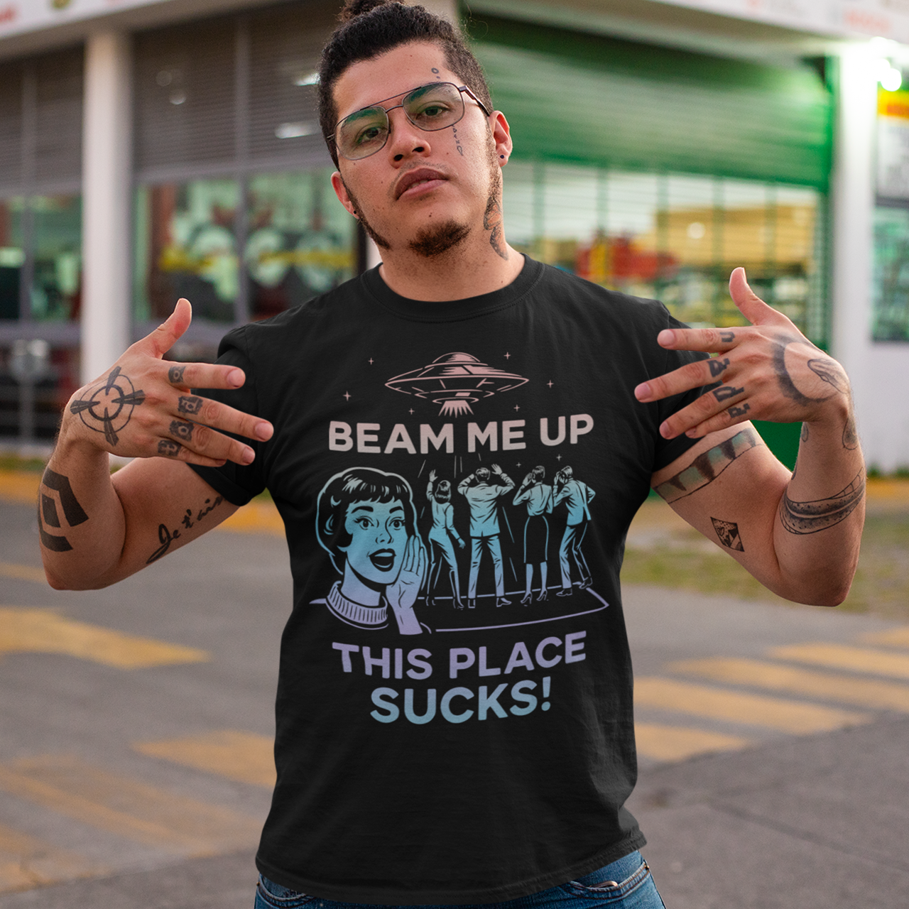 This snark-powered retro UFO t-shirt brings the perfect escape fantasy to life. A vintage-style flying saucer hovers above a crowd while a wide-eyed woman rallies for interstellar rescue, paired with the bold line “Beam Me Up, This Place Sucks!” The design has a classic pulp-sci-fi look that feels like it tumbled out of an old comic rack. Ideal for anyone who survives their days with eye rolls, cosmic daydreams, and a desire to be anywhere else in the galaxy.