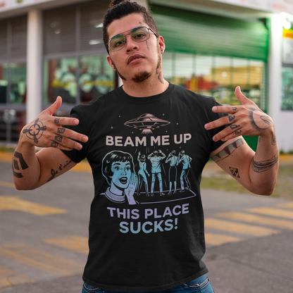 This snark-powered retro UFO t-shirt brings the perfect escape fantasy to life. A vintage-style flying saucer hovers above a crowd while a wide-eyed woman rallies for interstellar rescue, paired with the bold line “Beam Me Up, This Place Sucks!” The design has a classic pulp-sci-fi look that feels like it tumbled out of an old comic rack. Ideal for anyone who survives their days with eye rolls, cosmic daydreams, and a desire to be anywhere else in the galaxy.