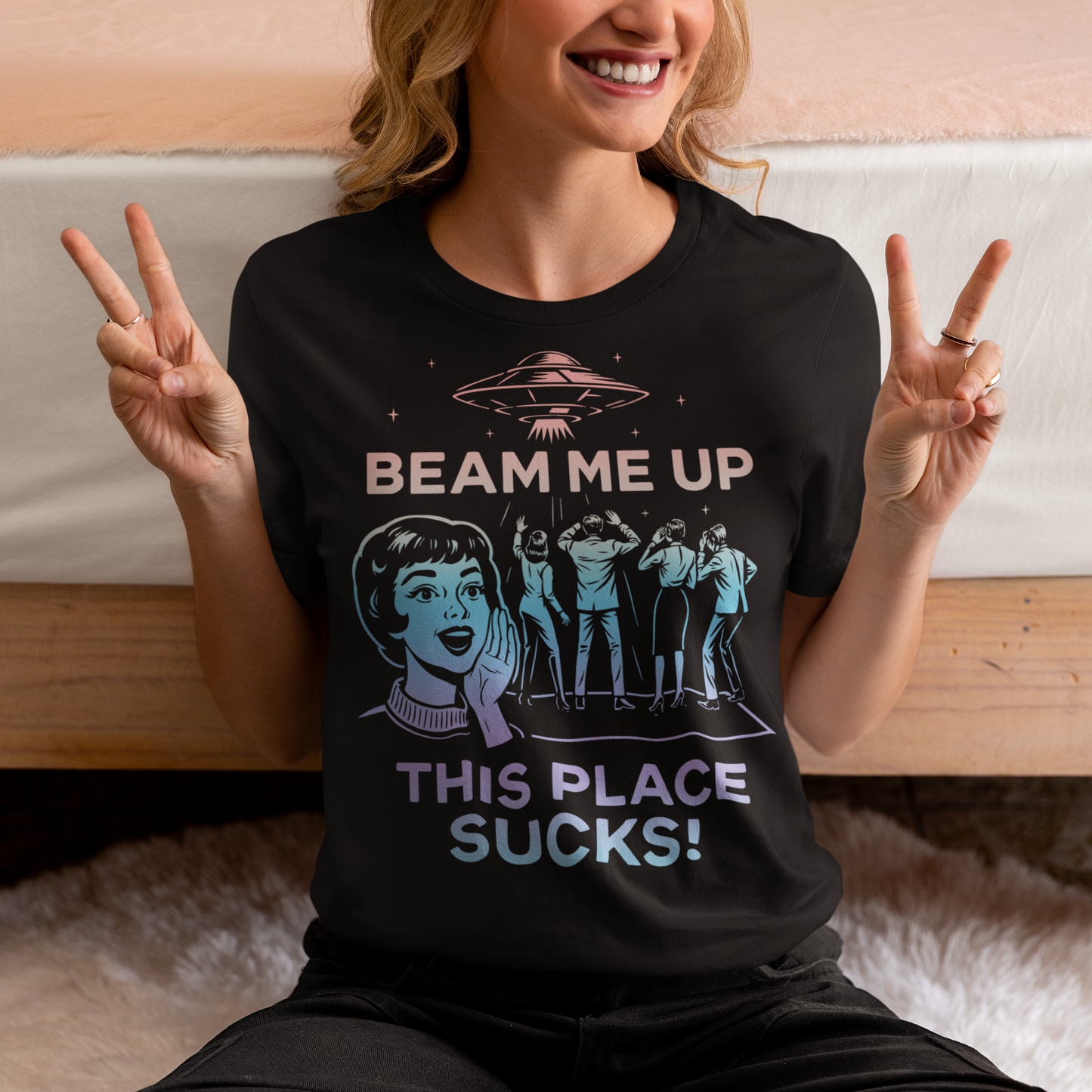 This snark-powered retro UFO t-shirt brings the perfect escape fantasy to life. A vintage-style flying saucer hovers above a crowd while a wide-eyed woman rallies for interstellar rescue, paired with the bold line “Beam Me Up, This Place Sucks!” The design has a classic pulp-sci-fi look that feels like it tumbled out of an old comic rack. Ideal for anyone who survives their days with eye rolls, cosmic daydreams, and a desire to be anywhere else in the galaxy.