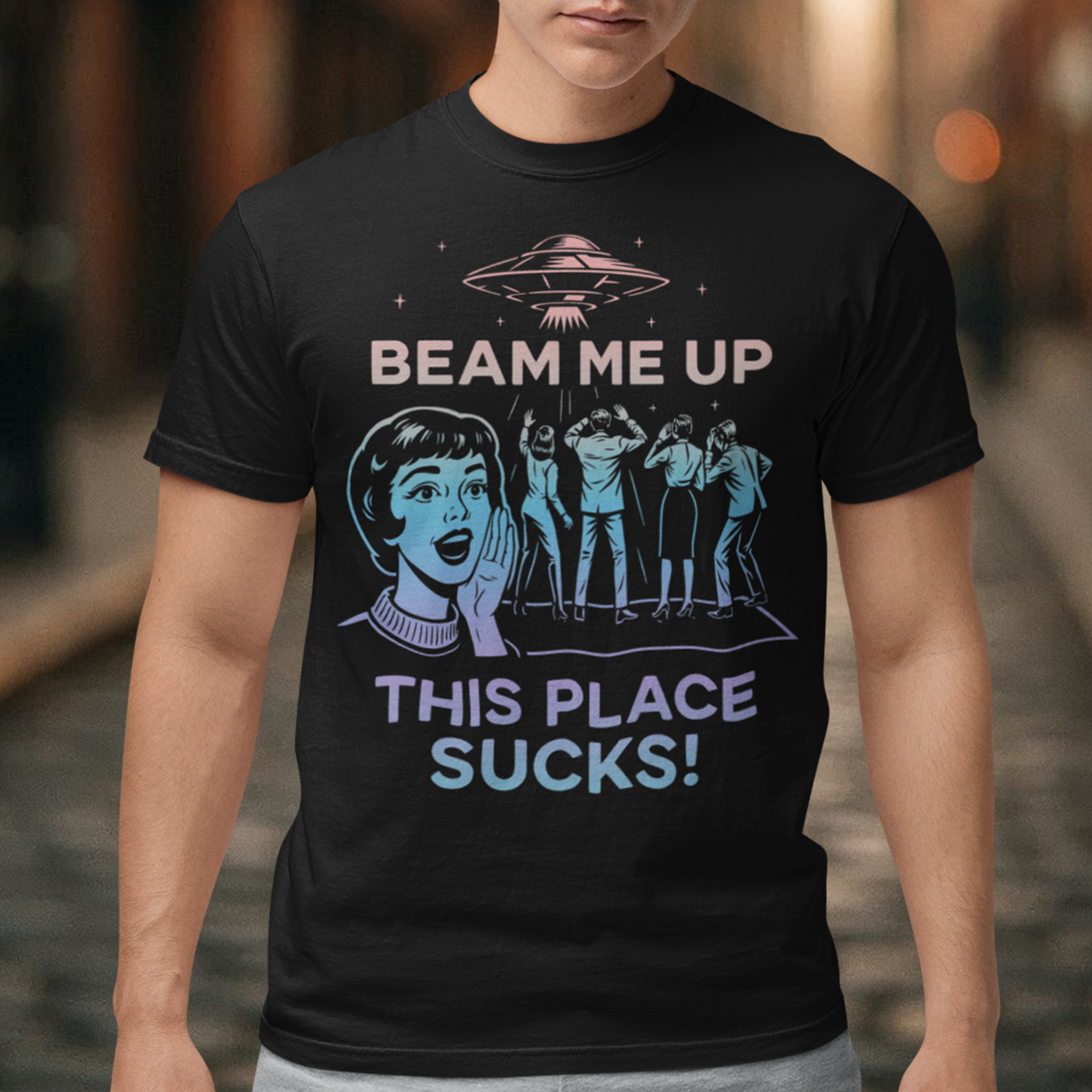 This snark-powered retro UFO t-shirt brings the perfect escape fantasy to life. A vintage-style flying saucer hovers above a crowd while a wide-eyed woman rallies for interstellar rescue, paired with the bold line “Beam Me Up, This Place Sucks!” The design has a classic pulp-sci-fi look that feels like it tumbled out of an old comic rack. Ideal for anyone who survives their days with eye rolls, cosmic daydreams, and a desire to be anywhere else in the galaxy.