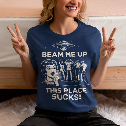This snark-powered retro UFO t-shirt brings the perfect escape fantasy to life. A vintage-style flying saucer hovers above a crowd while a wide-eyed woman rallies for interstellar rescue, paired with the bold line “Beam Me Up, This Place Sucks!” The design has a classic pulp-sci-fi look that feels like it tumbled out of an old comic rack. Ideal for anyone who survives their days with eye rolls, cosmic daydreams, and a desire to be anywhere else in the galaxy.