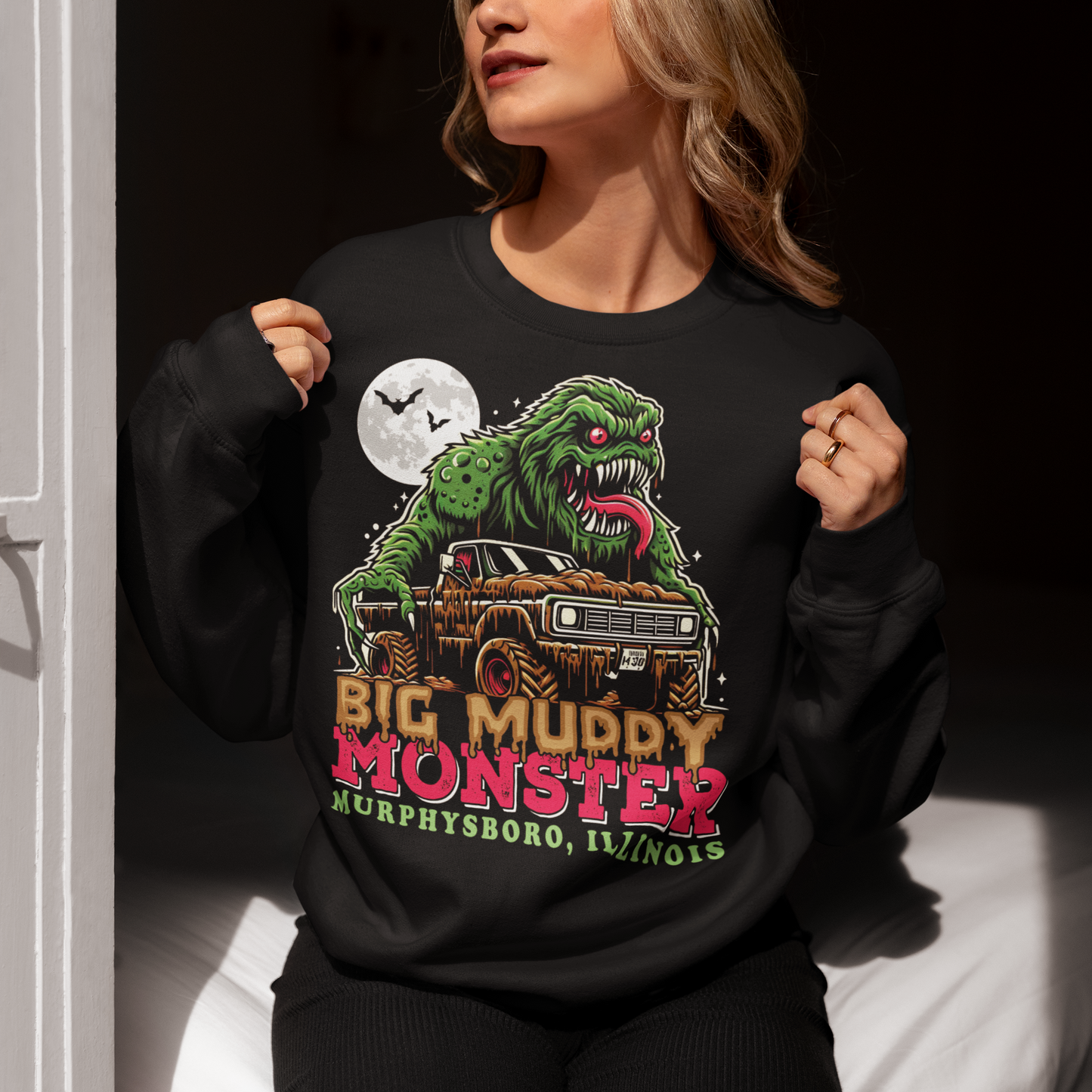 Black sweatshirt of the Murphysboro Mud Monster attacking a truck with text "BIG MUDDY MONSTER".