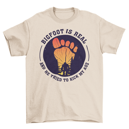 Cream t-shirt with a bigfoot silhouette on a sunset foot with text "BIGFOOT IS REAL AND HE TRIED TO KICK MY ASS".