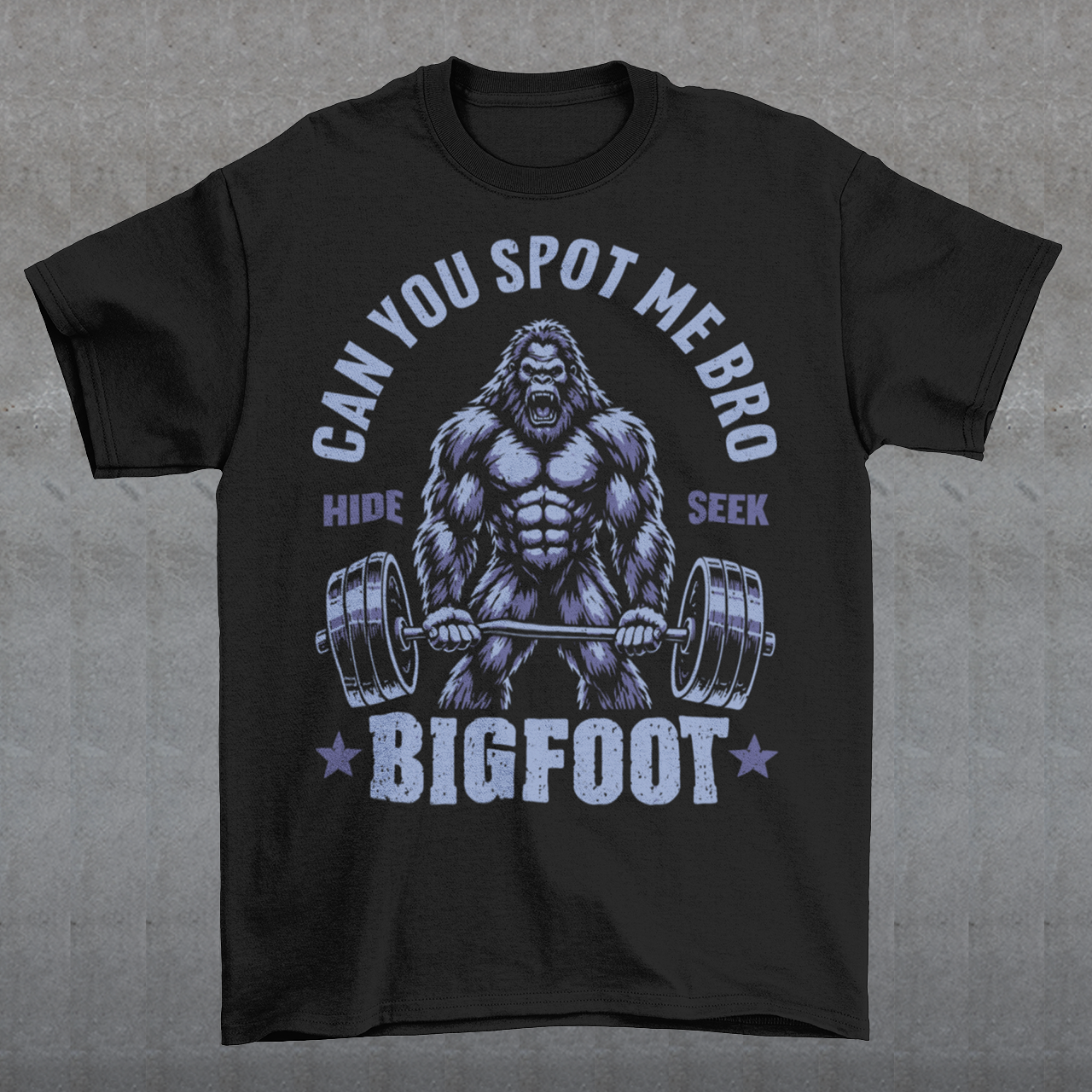 Black T-shirt featuring a muscular cartoon Bigfoot lifting a heavily loaded barbell. The graphic has bold white vintage-style lettering reading “CAN YOU SPOT ME BRO” above the Sasquatch, with “HIDE” and “SEEK” on either side and “BIGFOOT” beneath the weightlifter, flanked by stars. The design combines Bigfoot humor, gym culture, weightlifting, and cryptid themes.