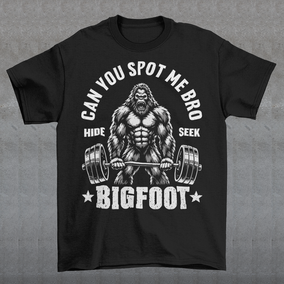 Black T-shirt featuring a muscular cartoon Bigfoot lifting a heavily loaded barbell. The graphic has bold white vintage-style lettering reading “CAN YOU SPOT ME BRO” above the Sasquatch, with “HIDE” and “SEEK” on either side and “BIGFOOT” beneath the weightlifter, flanked by stars. The design combines Bigfoot humor, gym culture, weightlifting, and cryptid themes.