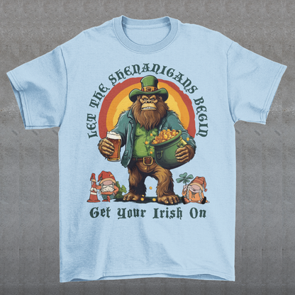 Get ready to celebrate St. Patrick's Day in style with our hilarious and festive Bigfoot-themed t-shirt! This shirt features everyone's favorite cryptid, Bigfoot, dressed in full leprechaun attire, complete with a green hat and shamrock-adorned vest. Bigfoot is depicted holding a frothy beer in one hand and a gleaming pot of gold in the other, ready to join in the festivities. Above this whimsical scene, bold text declares, "LET THE SHENANIGANS BEGIN."