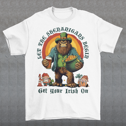 Get ready to celebrate St. Patrick's Day in style with our hilarious and festive Bigfoot-themed t-shirt! This shirt features everyone's favorite cryptid, Bigfoot, dressed in full leprechaun attire, complete with a green hat and shamrock-adorned vest. Bigfoot is depicted holding a frothy beer in one hand and a gleaming pot of gold in the other, ready to join in the festivities. Above this whimsical scene, bold text declares, "LET THE SHENANIGANS BEGIN."