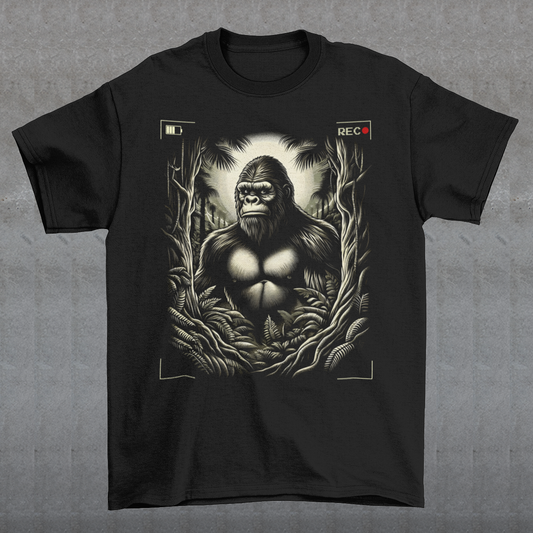 This t-shirt features a captivating and mysterious scene: Bigfoot, the legendary creature of folklore, is depicted peeking through dense, shadowy trees. The design captures the thrill of a rare sighting with intricate details, from the leaves rustling in the breeze to Bigfoot's curious expression.