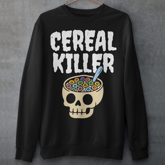 Black sweatshirt featuring the phrase “Cereal Killer” in large distressed white letters above a cartoon skull used as a cereal bowl filled with colorful cereal loops and a spoon. Funny dark humor design combining spooky Halloween style with breakfast pun humor.