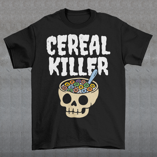 Black t-shirt featuring the phrase “Cereal Killer” in large distressed white letters above a cartoon skull used as a cereal bowl filled with colorful cereal loops and a spoon. Funny dark humor design combining spooky Halloween style with breakfast pun humor.
