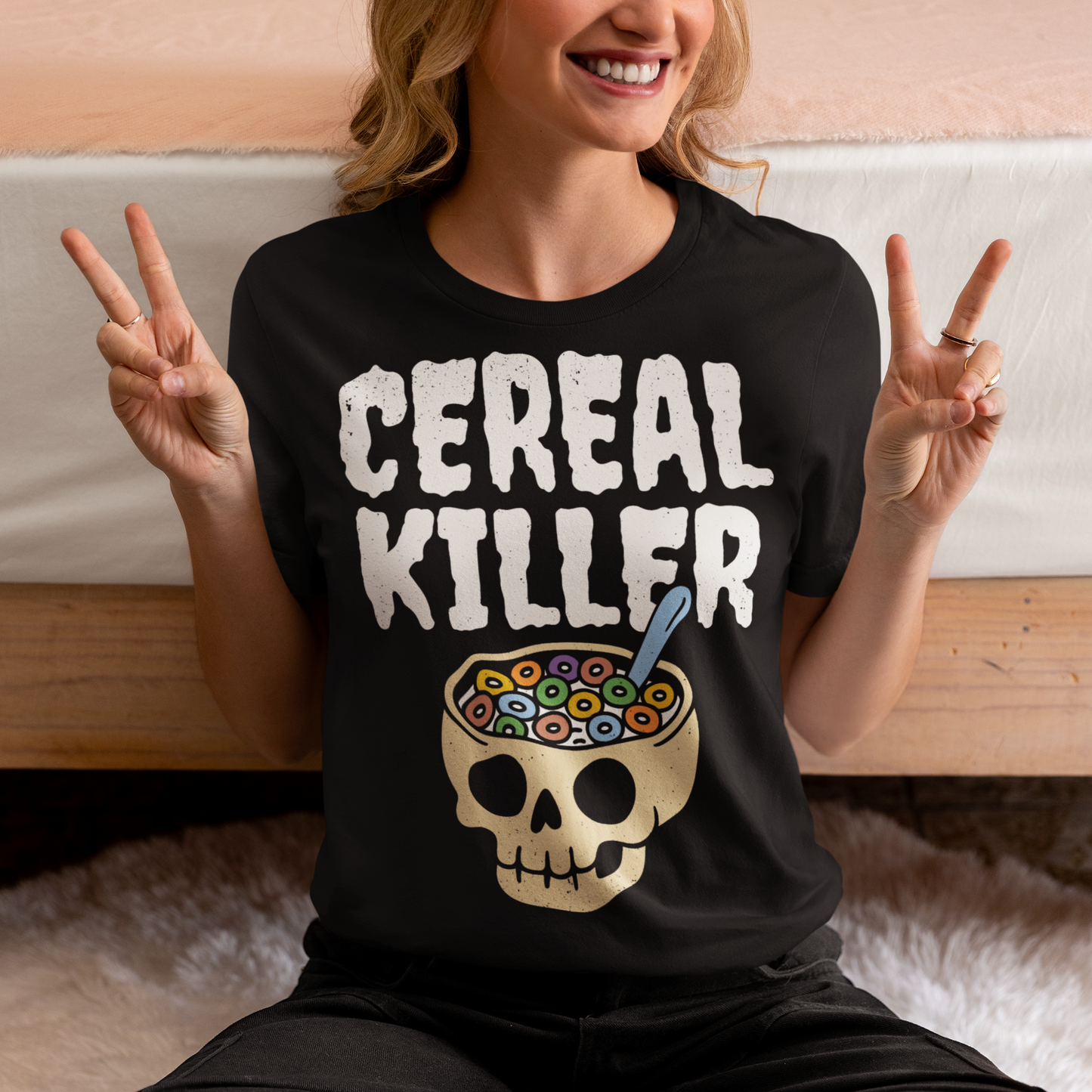 Black t-shirt featuring the phrase “Cereal Killer” in large distressed white letters above a cartoon skull used as a cereal bowl filled with colorful cereal loops and a spoon. Funny dark humor design combining spooky Halloween style with breakfast pun humor.