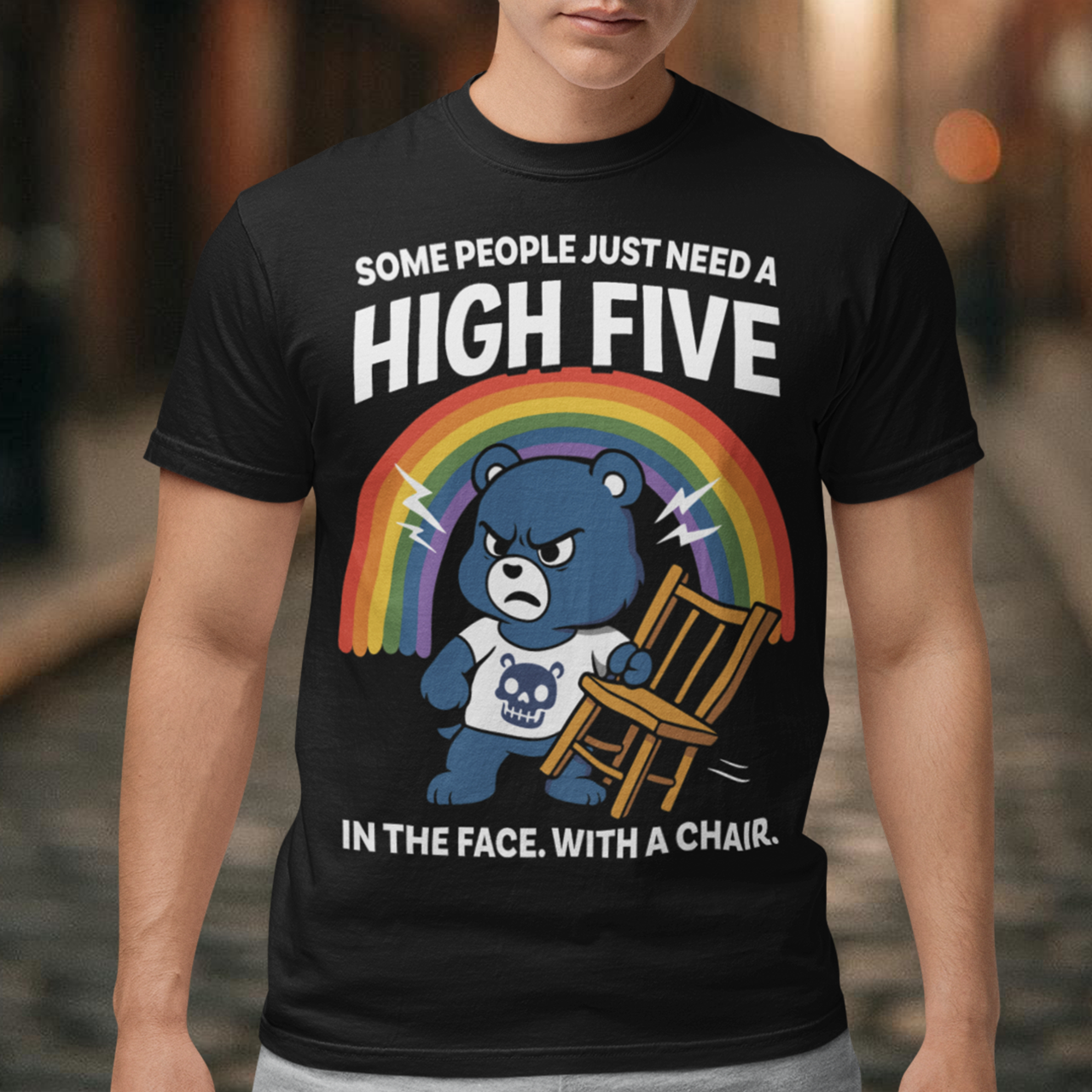 CHAIR BEAR SKULL HIGH FIVE T-SHIRT. Sweet meets savage in this hilariously bold “High Five” Bear t-shirt. At first glance, it’s all rainbows and retro cartoon charm, but look a little closer and you’ll catch the punchline. Featuring a grumpy blue bear under a bright rainbow, gripping a chair with questionable intentions, this design flips cute nostalgia into edgy humor with a perfectly timed twist.