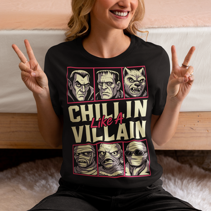 Black t-shirt featuring the phrase "Chillin Like A Villain" with six classic horror monster portraits, including a vampire, Frankenstein's monster, werewolf, mummy, swamp creature, and the Invisible Man. The retro-inspired graphic uses distressed vintage styling with bold cream and pink lettering, making it a fun horror-themed shirt for Halloween, monster movie fans, goth fashion lovers, and classic horror enthusiasts.