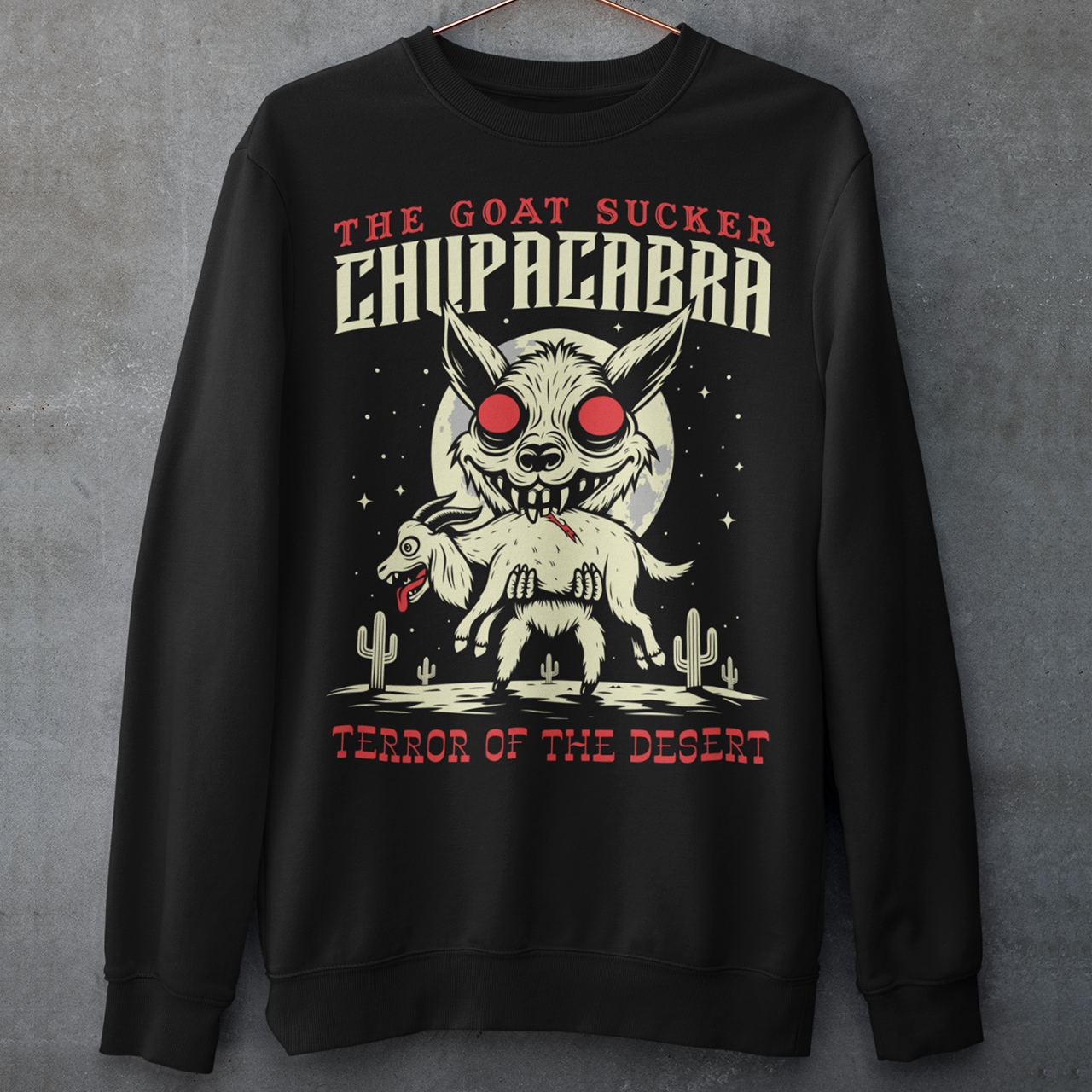 Black sweatshirt of a chupacabra sucking on a goat in the desert with text above THE GOAT SUCKER CHUPACABRA ang text below TERROR OF THE DESERT.