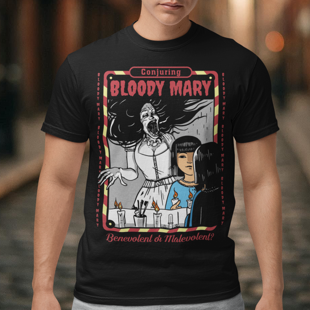 Dare to look twice. This chilling tee features a haunting design of a girl staring into a mirror—only to find Bloody Mary staring back from the reflection. Above, the bold words “Conjuring Bloody Mary” summon the legend, while below, the question “Benevolent or malevolent?” dares the viewer to decide. This shirt is perfect for horror fans, urban legend lovers, and anyone who enjoys walking the line between myth and reality.