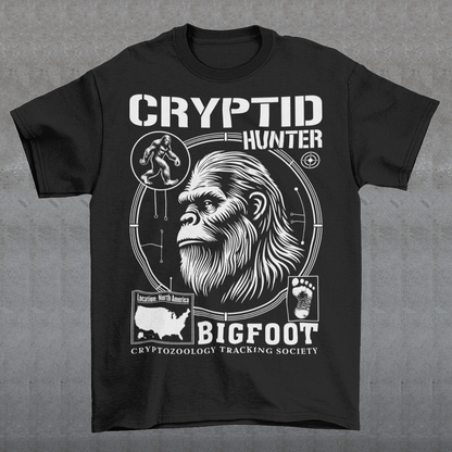 Illustration of a cryptozoology-themed t-shirt featuring a stylized image of Bigfoot's head, shown with shaggy fur, deep-set eyes, and a mysterious expression. The artwork has a bold, rugged design in earthy tones, emphasizing the mythical nature of the creature. Above the image, the words "CRYPTID HUNTER" are prominently displayed in large, distressed lettering, suggesting adventure and mystery. The design appeals to fans of folklore, legends, and unexplained phenomena.