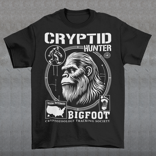 Illustration of a cryptozoology-themed t-shirt featuring a stylized image of Bigfoot's head, shown with shaggy fur, deep-set eyes, and a mysterious expression. The artwork has a bold, rugged design in earthy tones, emphasizing the mythical nature of the creature. Above the image, the words "CRYPTID HUNTER" are prominently displayed in large, distressed lettering, suggesting adventure and mystery. The design appeals to fans of folklore, legends, and unexplained phenomena.