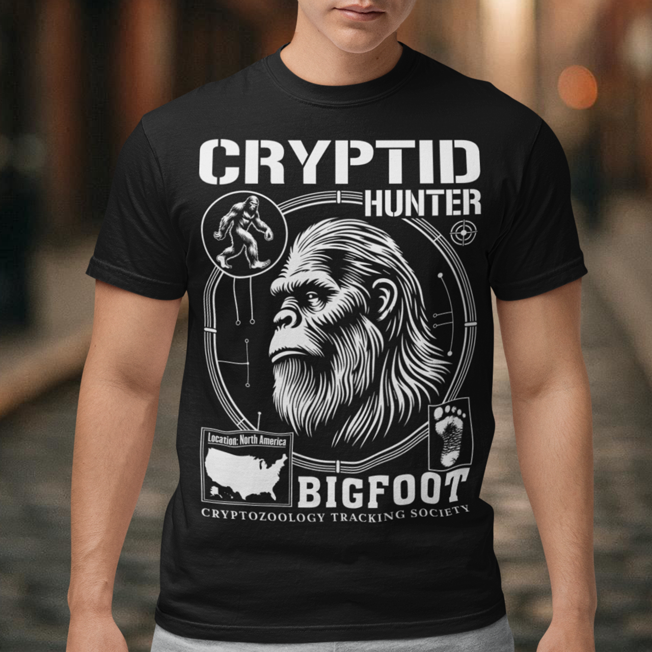 Illustration of a cryptozoology-themed t-shirt featuring a stylized image of Bigfoot's head, shown with shaggy fur, deep-set eyes, and a mysterious expression. The artwork has a bold, rugged design in earthy tones, emphasizing the mythical nature of the creature. Above the image, the words "CRYPTID HUNTER" are prominently displayed in large, distressed lettering, suggesting adventure and mystery. The design appeals to fans of folklore, legends, and unexplained phenomena.