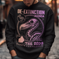 A graphic sweatshirt featuring a stylized illustration of a dodo bird, standing upright with a proud, almost defiant expression. The dodo is depicted in vibrant colors, blending realism with a slightly cartoonish flair. Above the bird, bold, capitalized text reads "DE-EXTINCTION AGENDA" in a futuristic font, suggesting a science fiction or activist tone. The design evokes themes of genetic engineering, conservation, and the revival of extinct species. The shirt is a statement piece with humor.