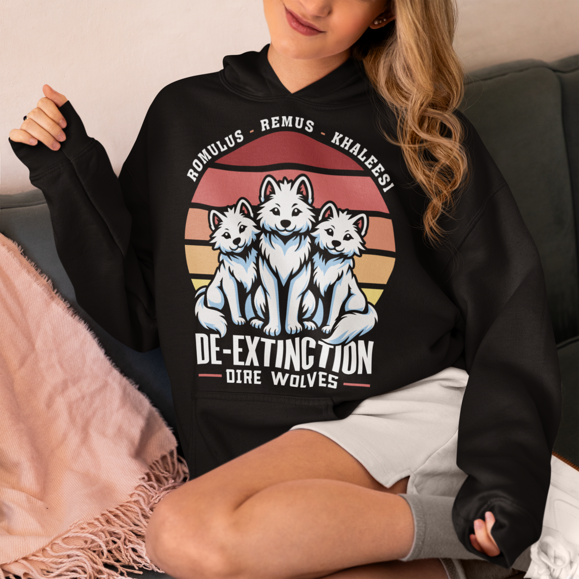Black hoodie of three Dire Wolves sitting in front of a retro sun with text below DE-EXTINCTION.