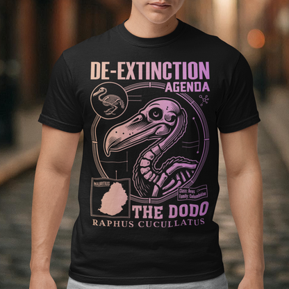 A graphic t-shirt featuring a stylized illustration of a dodo bird, standing upright with a proud, almost defiant expression. The dodo is depicted in vibrant colors, blending realism with a slightly cartoonish flair. Above the bird, bold, capitalized text reads "DE-EXTINCTION AGENDA" in a futuristic font, suggesting a science fiction or activist tone. The design evokes themes of genetic engineering, conservation, and the revival of extinct species. The shirt is a statement piece with humor.
