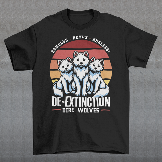 A graphic t-shirt design featuring three majestic Dire Wolves sitting side by side, facing forward with alert expressions. Behind them is a large, stylized retro sun composed of horizontal stripes in warm tones of orange, red, and yellow, evoking a vintage 80s aesthetic. Beneath the wolves, bold text reads “DE-EXTINCTION,” suggesting the return of these prehistoric predators. The design blends prehistoric imagery with nostalgic retro-futurism.