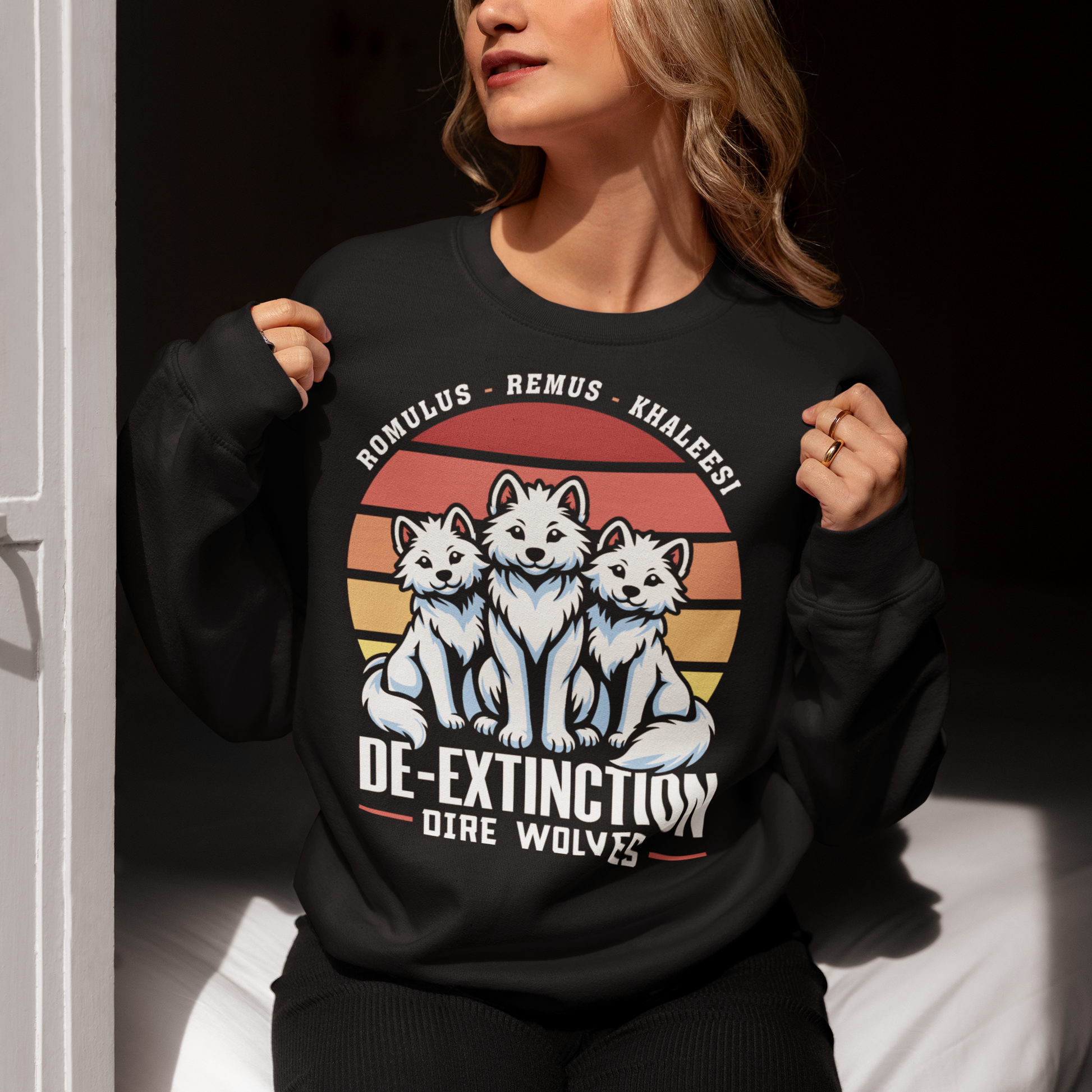 Black sweatshirt of three Dire Wolves sitting in front of a retro sun with text below DE-EXTINCTION.