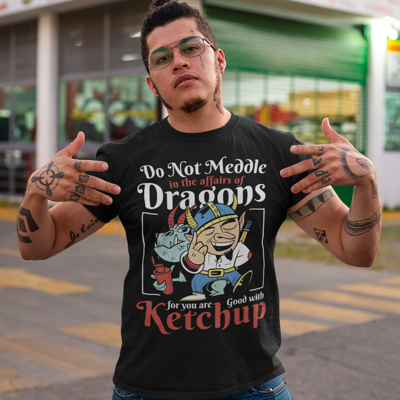 Black t-shirt of a dragon holding a bottle of ketchup standing behind a viking  with text DO NOT MEDDLE IN THE AFFAIRS OF DRAGONS FOR YOU ARE GOOD WITH KETCHUP.