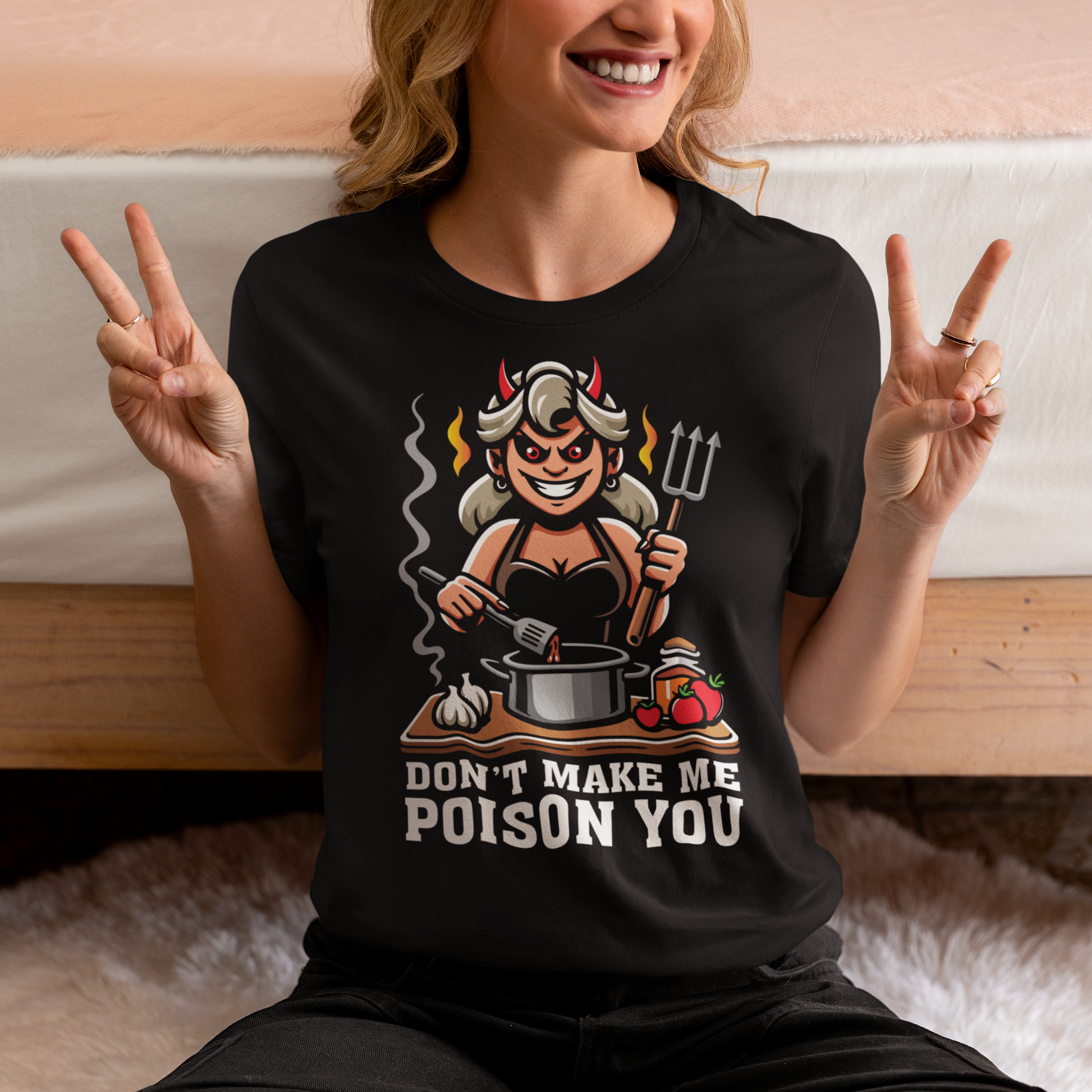 Black t-shirt of a devil woman cooking food with text underneath DON'T MAKE ME POISON YOU.