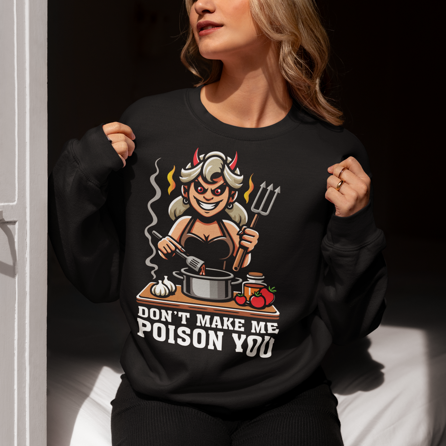 Black sweatshirt of a devil woman cooking food with text underneath DONT MAKE ME POISON YOU.