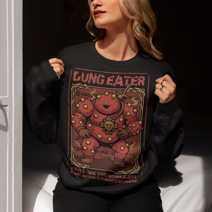 This black sweatshirt features a grim, illustrated tribute to one of dark fantasy’s most unsettling figures Dung Eater. The hulking, corrupted character dominates the design, rendered in deep crimson tones with weathered textures and ornate framing that echo cursed tomes and forgotten prophecies. The bold title above and the chilling line below give the artwork the feeling of a forbidden page torn from a doomed legend.
