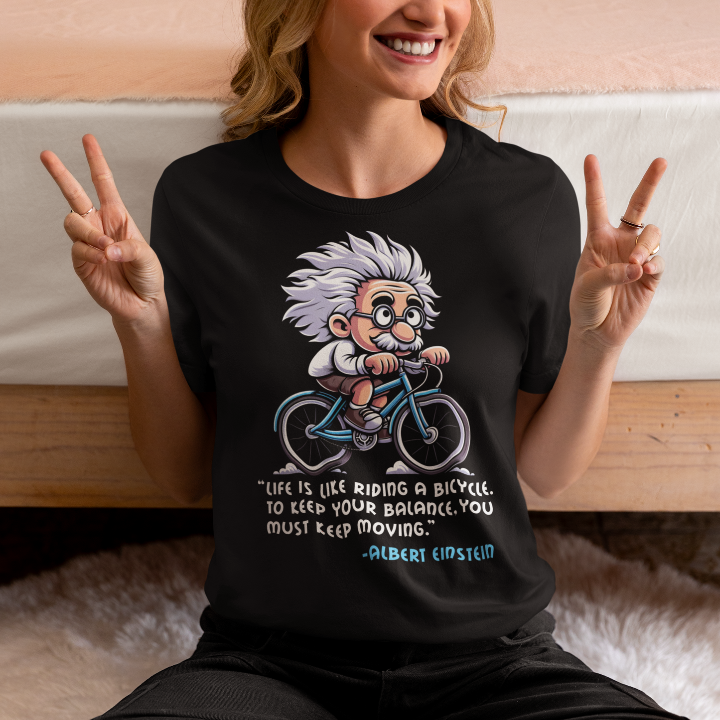 Black t-shirt of Albert Einstein cycling a bike with motivational quote.