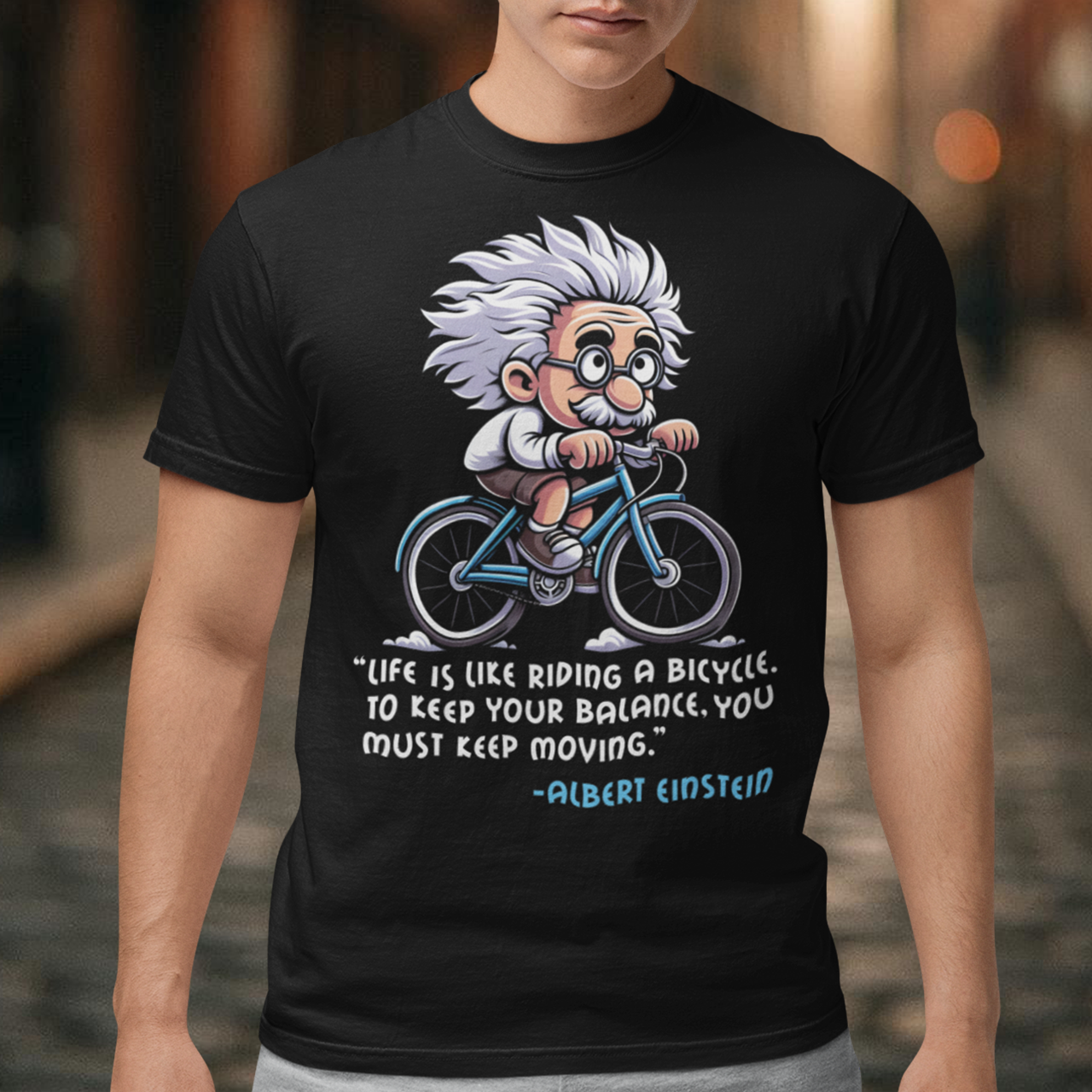 Discover the perfect blend of intellect and inspiration with our "Einstein Cycling" T-shirt. This unique design features the legendary physicist Albert Einstein enjoying a leisurely bike ride, embodying both his playful spirit and his profound wisdom. Below the whimsical illustration, you'll find one of Einstein's most motivational quotes: "Life is like riding a bicycle. To keep your balance, you must keep moving."