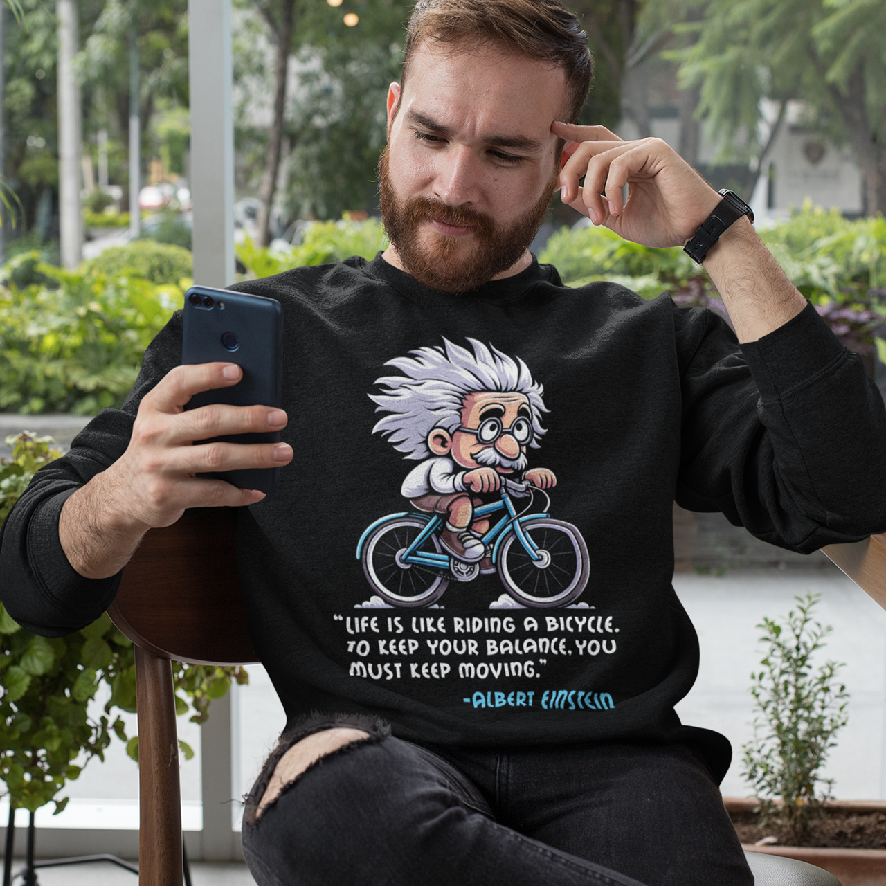 Black sweatshirt of Albert Einstein cycling a bike with motivational quote.