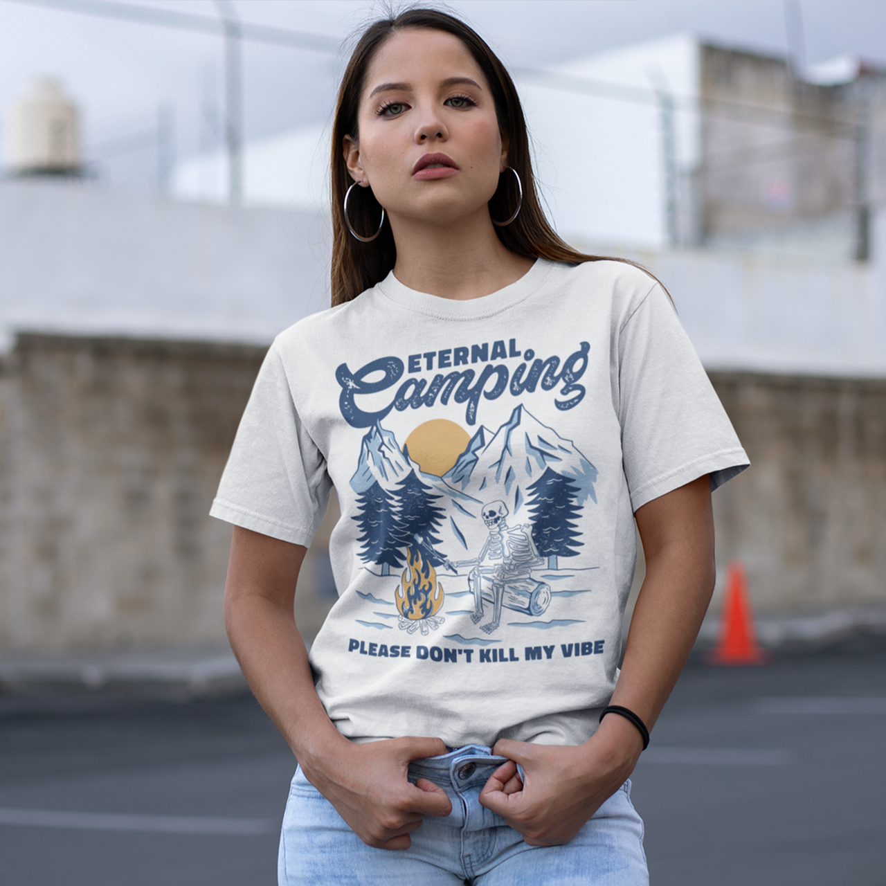 White t-shirt of a skeleton sitting by a fire in snowy forest with text "ETERNAL CAMPING".