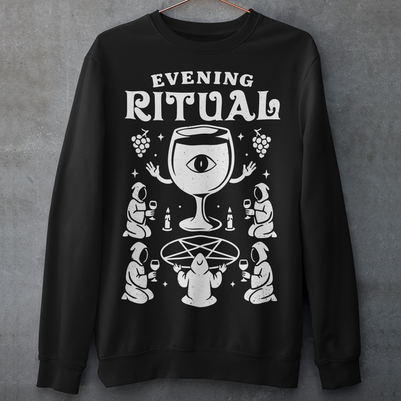 Black sweatshirt featuring a white occult-style graphic with the text “Evening Ritual.” Design shows hooded figures gathered around a pentagram performing a ritual with wine glasses, candles, grapes, and a large mystical wine goblet with an eye symbol. Spooky gothic and illuminati-inspired humor combined with wine lover aesthetics.