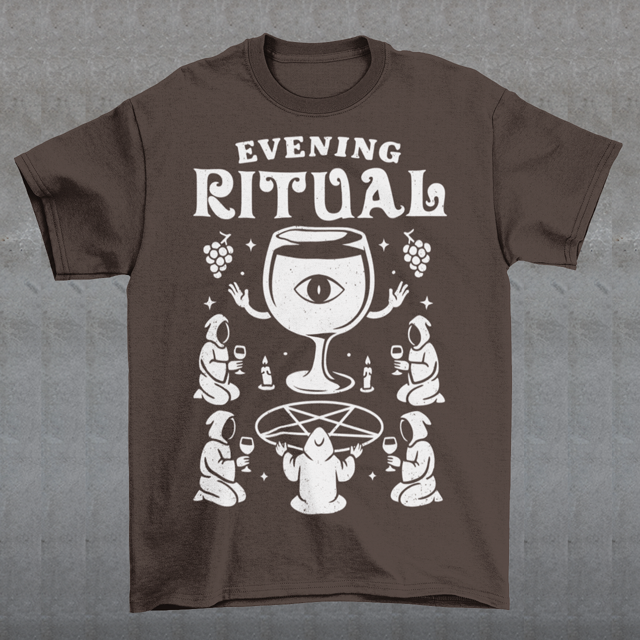 Brown t-shirt featuring a white occult-style graphic with the text “Evening Ritual.” Design shows hooded figures gathered around a pentagram performing a ritual with wine glasses, candles, grapes, and a large mystical wine goblet with an eye symbol. Spooky gothic and illuminati-inspired humor combined with wine lover aesthetics.