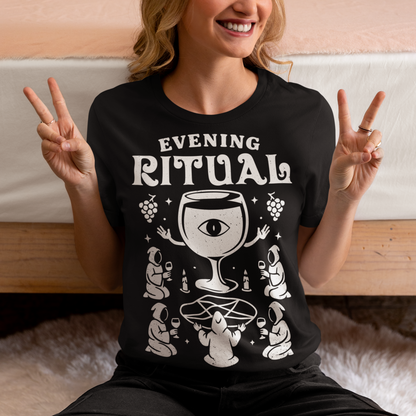 Black t-shirt featuring a white occult-style graphic with the text “Evening Ritual.” Design shows hooded figures gathered around a pentagram performing a ritual with wine glasses, candles, grapes, and a large mystical wine goblet with an eye symbol. Spooky gothic and illuminati-inspired humor combined with wine lover aesthetics.
