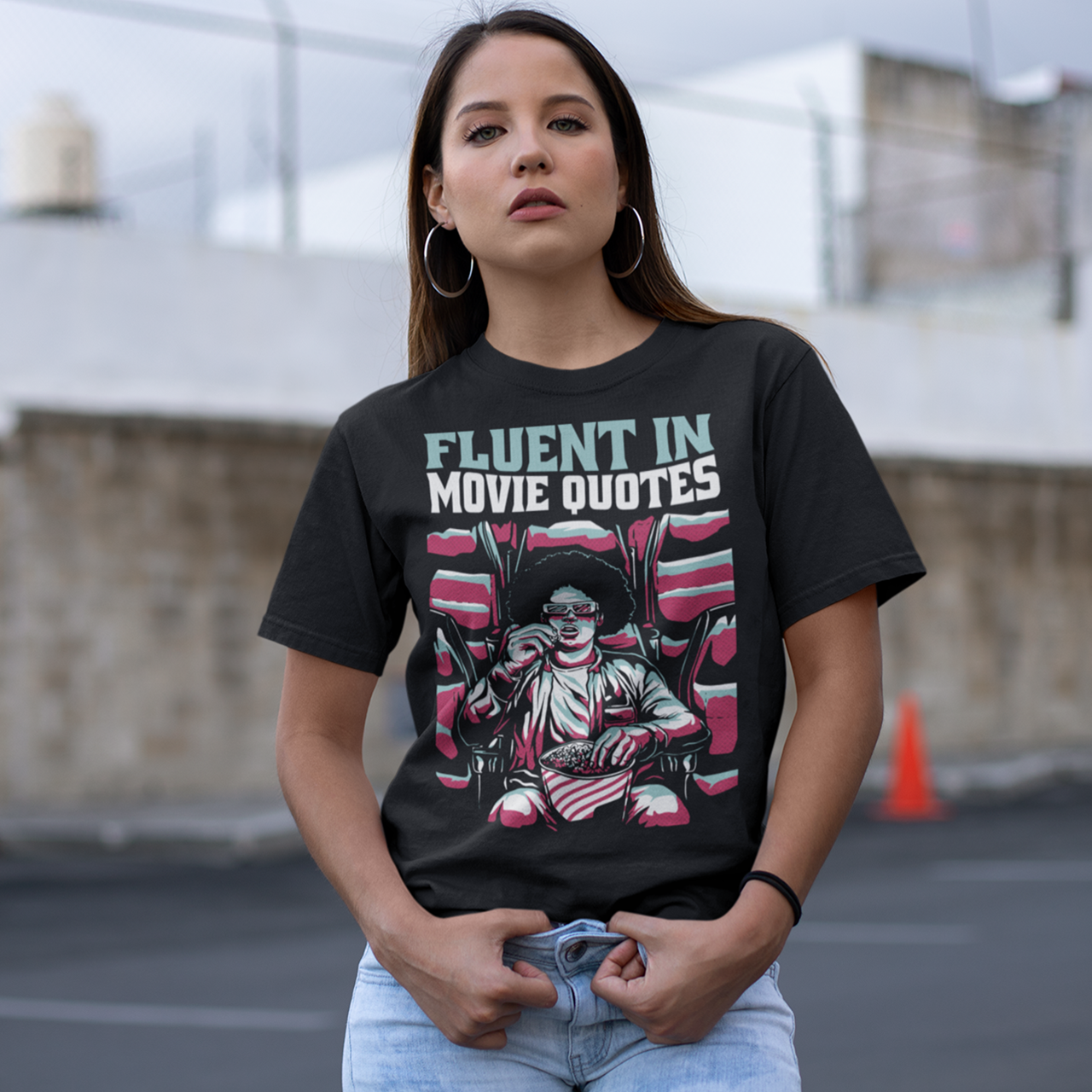 Black t-shirt with a person wearing 3D glasses watching a movie in a cinema eating popcorn  with text "FLUENT IN MOVIE QUOTES".