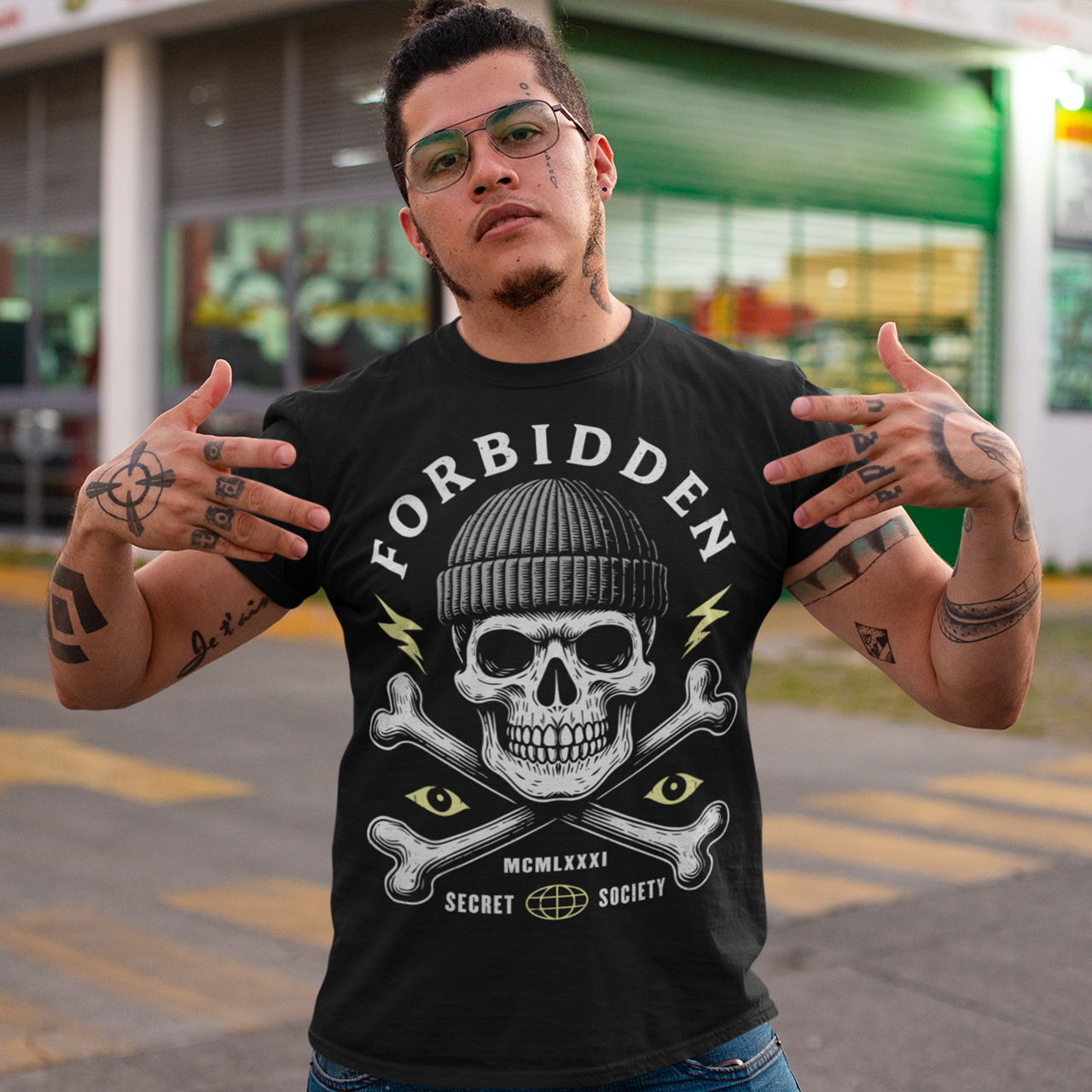 At the center sits a stark skull in a knit beanie, framed by crossed bones, watchful eyes, and crackling lightning bolts. Bold lettering reads Forbidden, with subtle details like Roman numerals and “Secret Society” giving the design the air of an underground emblem or outlaw insignia. The muted cream and acid-yellow accents pop against the black fabric, creating a gritty, modern occult aesthetic.