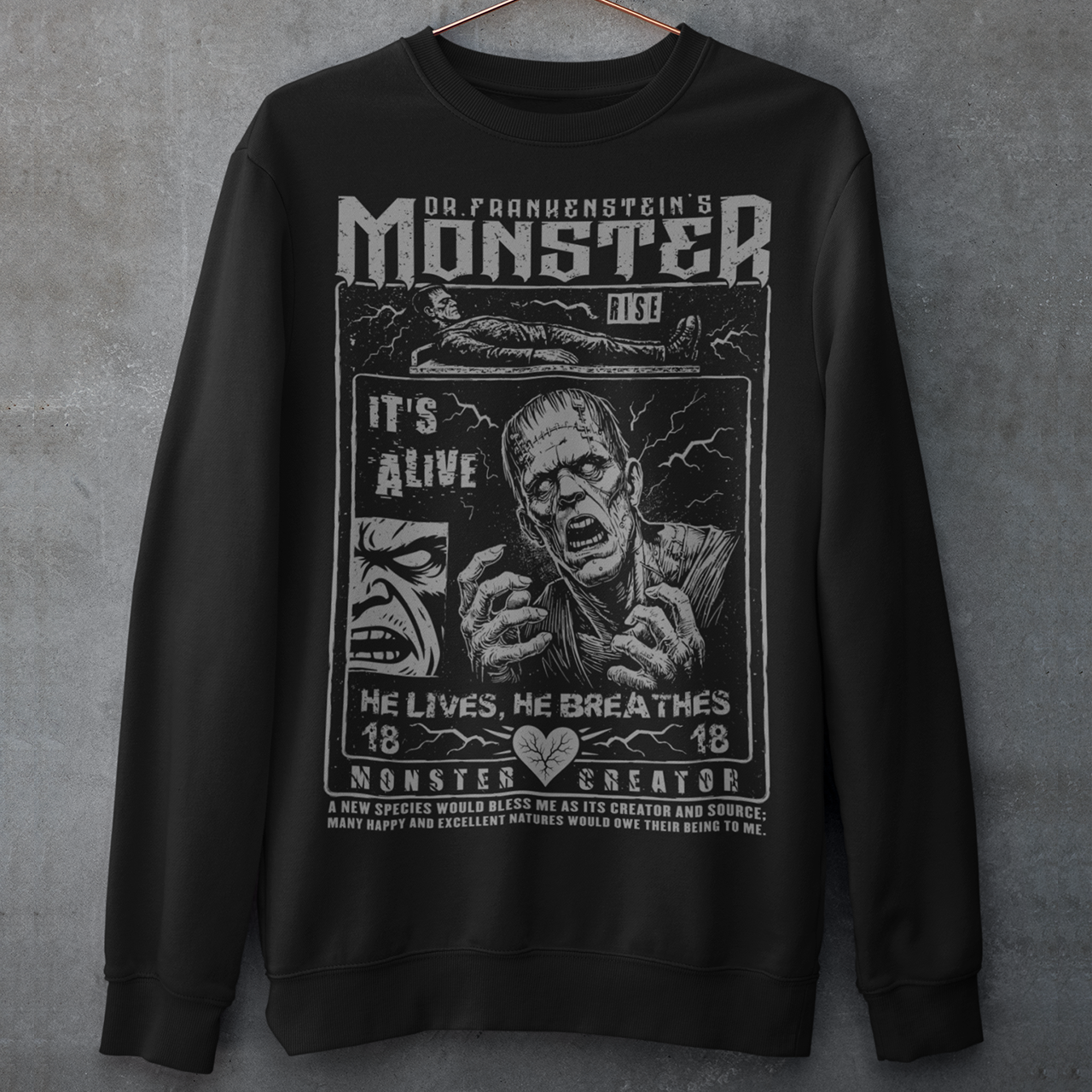 Black horror-themed sweatshirt featuring a vintage Frankenstein monster graphic in distressed gray print. The design includes comic-style panels with lightning bolts, Dr. Frankenstein’s monster rising from a lab table, and bold text reading “It’s Alive.” Gothic typography and retro horror artwork give the shirt a classic monster movie aesthetic, perfect for Halloween, horror fans, gothic fashion lovers, and collectors of vintage spooky apparel.