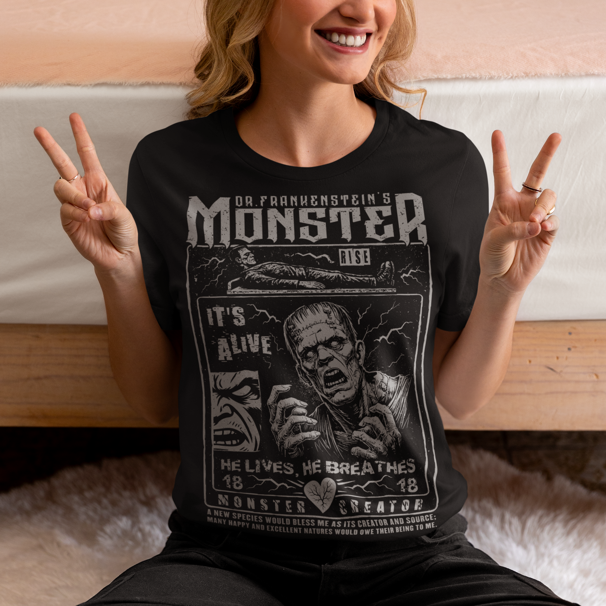 Black horror-themed t-shirt featuring a vintage Frankenstein monster graphic in distressed gray print. The design includes comic-style panels with lightning bolts, Dr. Frankenstein’s monster rising from a lab table, and bold text reading “It’s Alive.” Gothic typography and retro horror artwork give the shirt a classic monster movie aesthetic, perfect for Halloween, horror fans, gothic fashion lovers, and collectors of vintage spooky apparel.