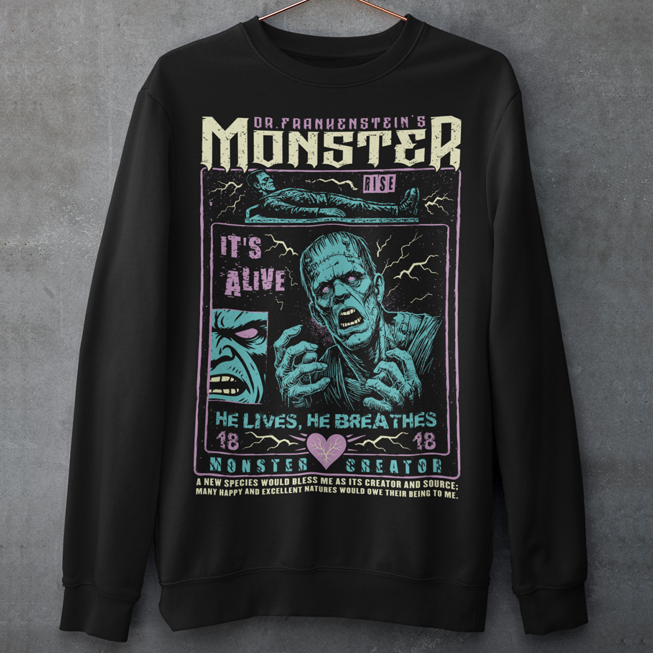 Black horror-themed sweatshirt featuring a vintage Frankenstein monster graphic in distressed gray print. The design includes comic-style panels with lightning bolts, Dr. Frankenstein’s monster rising from a lab table, and bold text reading “It’s Alive.” Gothic typography and retro horror artwork give the shirt a classic monster movie aesthetic, perfect for Halloween, horror fans, gothic fashion lovers, and collectors of vintage spooky apparel.