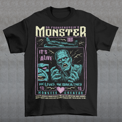 Black horror-themed t-shirt featuring a vintage Frankenstein monster graphic in distressed gray print. The design includes comic-style panels with lightning bolts, Dr. Frankenstein’s monster rising from a lab table, and bold text reading “It’s Alive.” Gothic typography and retro horror artwork give the shirt a classic monster movie aesthetic, perfect for Halloween, horror fans, gothic fashion lovers, and collectors of vintage spooky apparel.