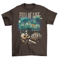 Brown t-shirt of a skeleton buried in the ground with plants growning up from the ground with text "FULL OF LIFE".